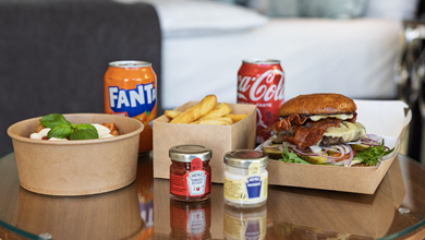 Et bord dækket med en lækker burger, sprøde pommes frites og en forfriskende sodavand, klar til at blive nydt.